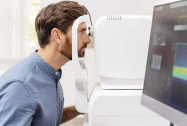 Young man fixing in a non-mydriatic retinal camera equipment. Diagnostic concept